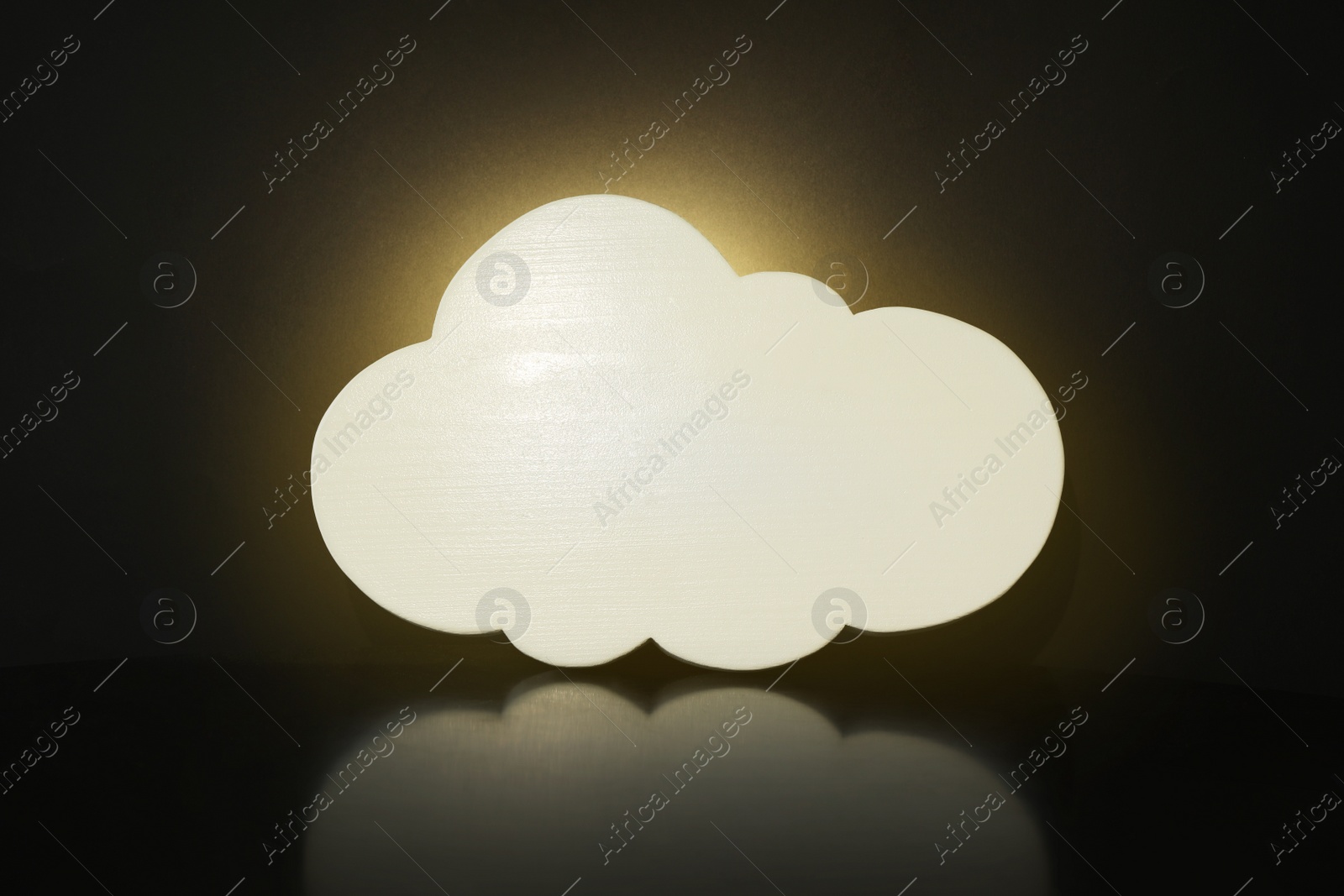 Photo of Cloud shaped glowing night lamp on black background