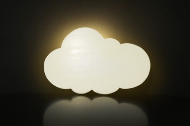 Photo of Cloud shaped glowing night lamp on black background
