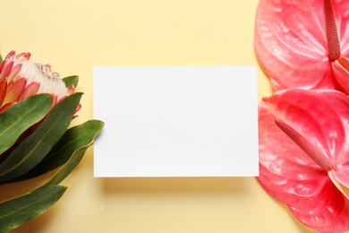 Photo of Creative composition with tropical flowers and card on color background, top view