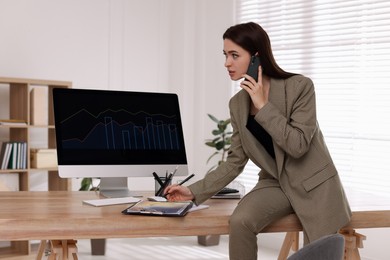 Photo of Businesswoman talking on phone while working in office. Forex trading