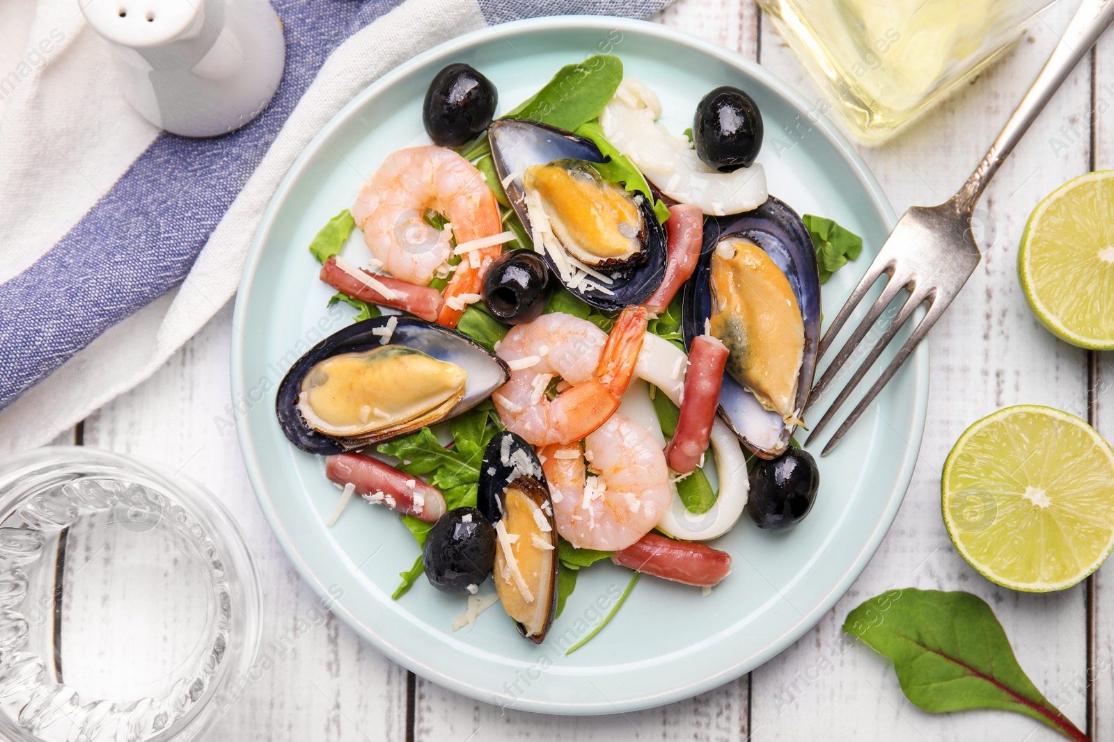 Photo of Plate of delicious salad with seafood on white wooden table, flat lay