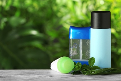 Photo of Natural deodorants with aloe and mint on wooden table against blurred green background. Space for text