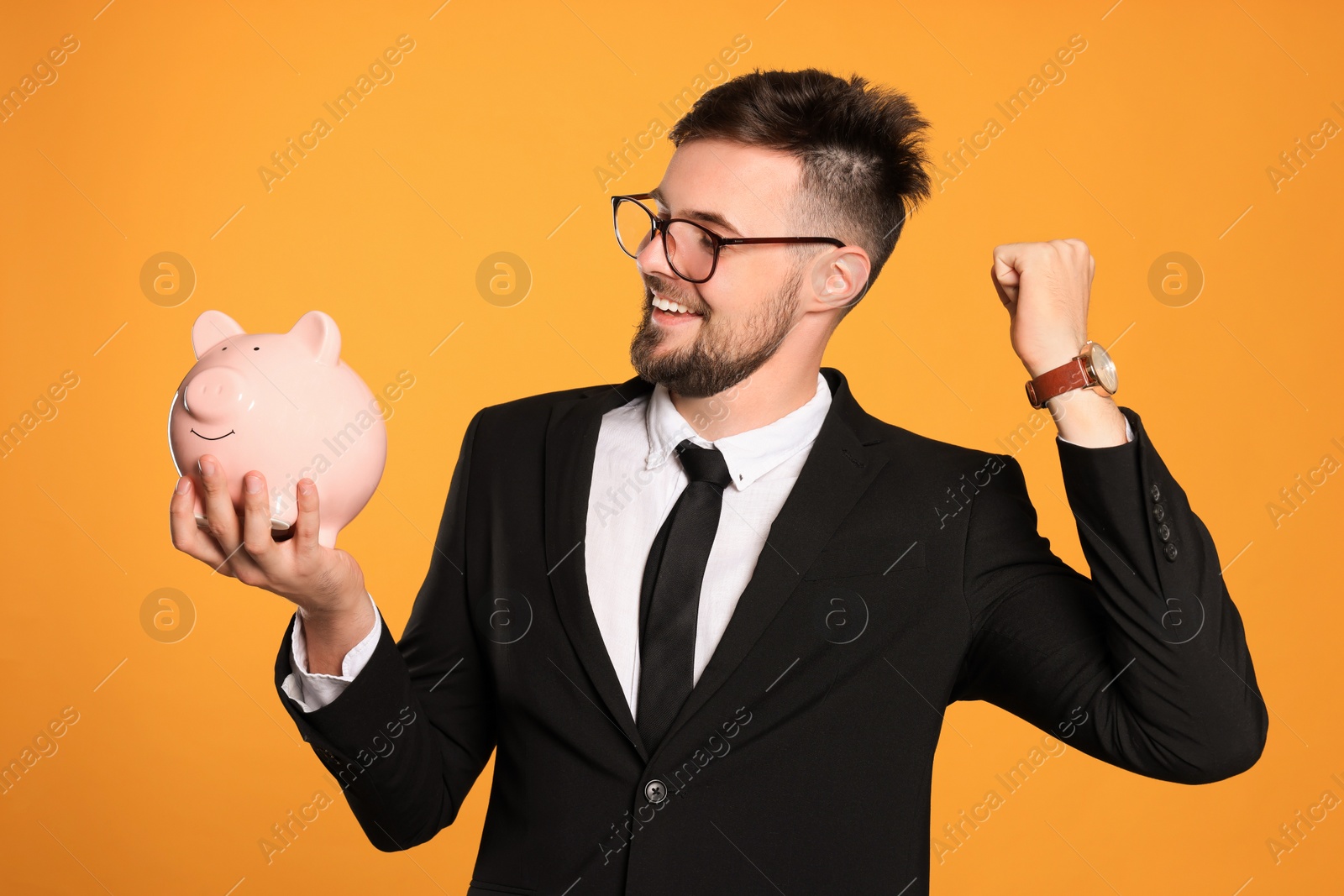 Photo of Happy businessman with piggy bank on orange background