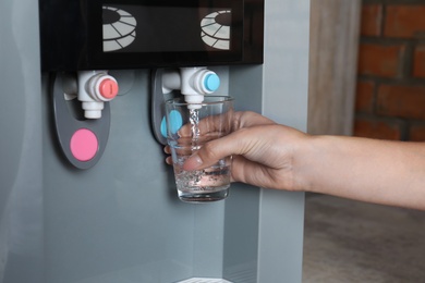 Photo of Woman filling glass from water cooler, closeup