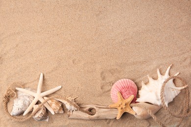 Photo of Beautiful starfishes, rope and sea shells on sand, flat lay. Space for text