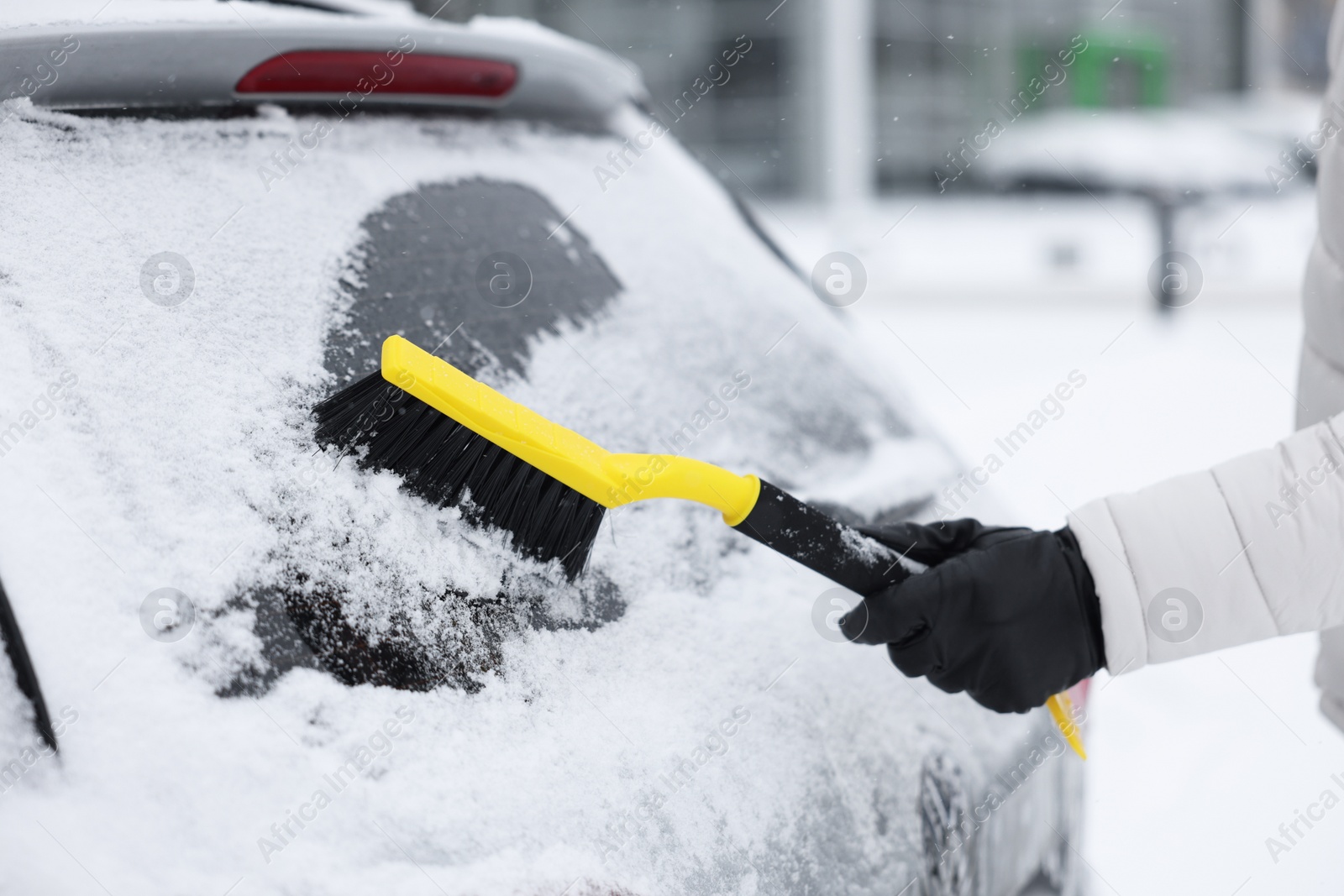 Photo of Man cleaning snow from car window outdoors, closeup