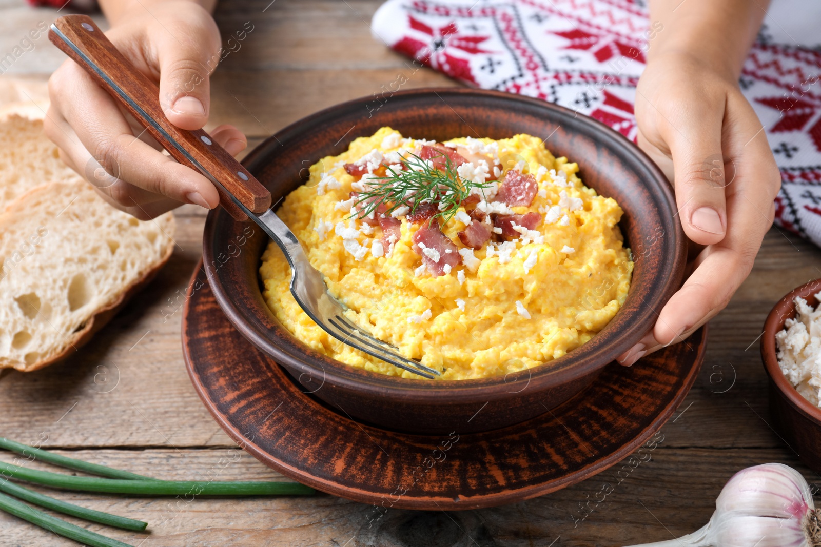 Photo of Woman eating banosh with brynza and pork cracklings at wooden table, closeup. Traditional Ukrainian dish