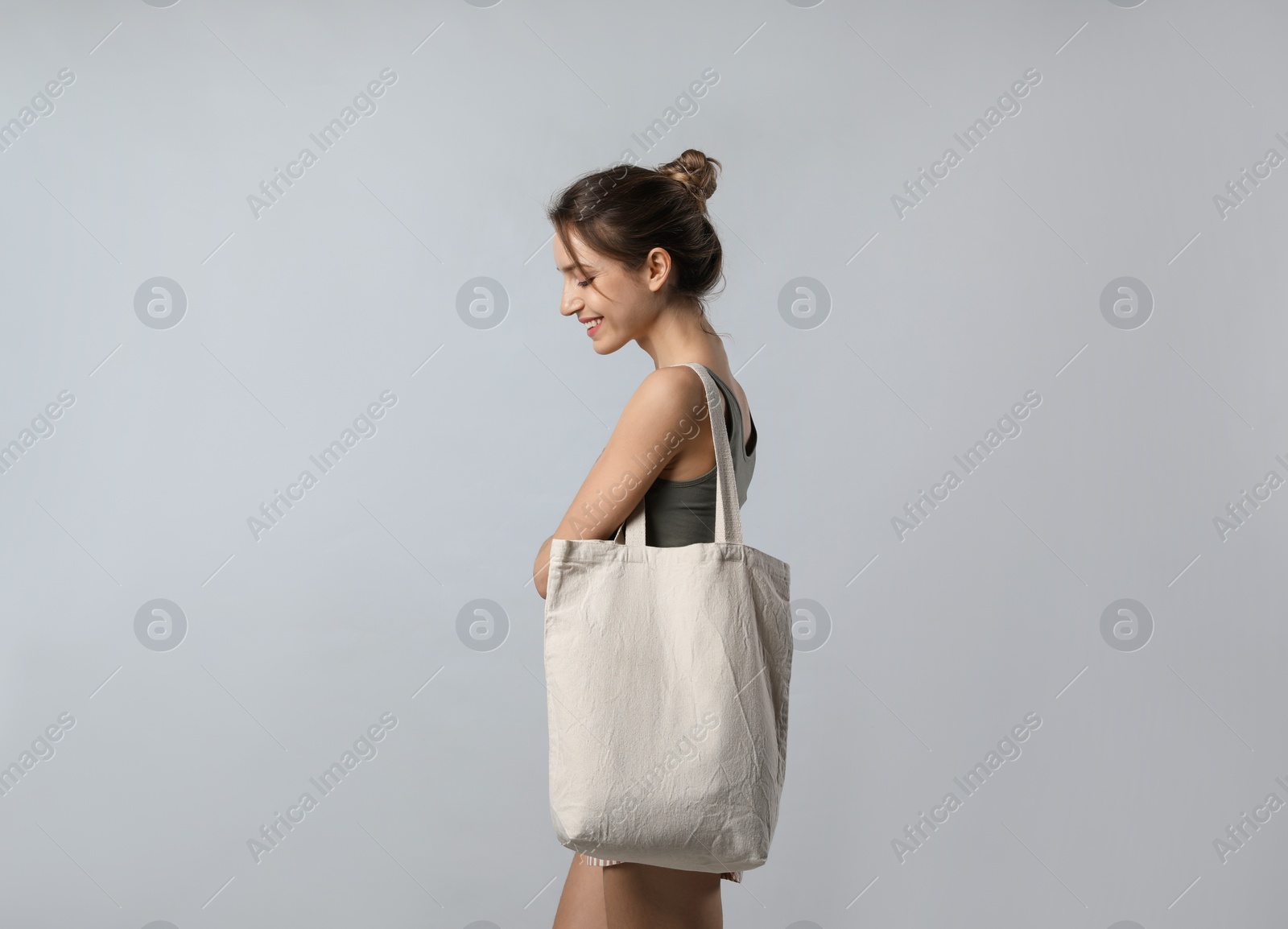 Photo of Happy young woman with blank eco friendly bag on light background