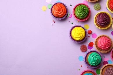 Flat lay composition with delicious colorful cupcakes on violet background. Space for text