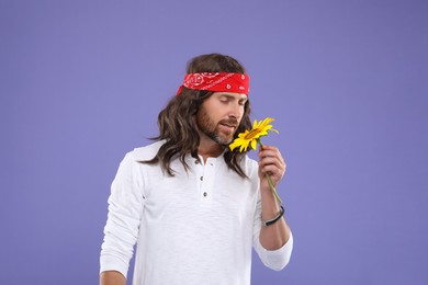 Photo of Stylish hippie man with sunflower on violet background