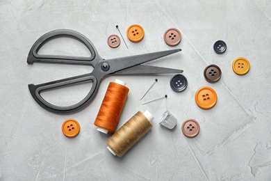 Photo of Set of tailoring accessories on light background, top view