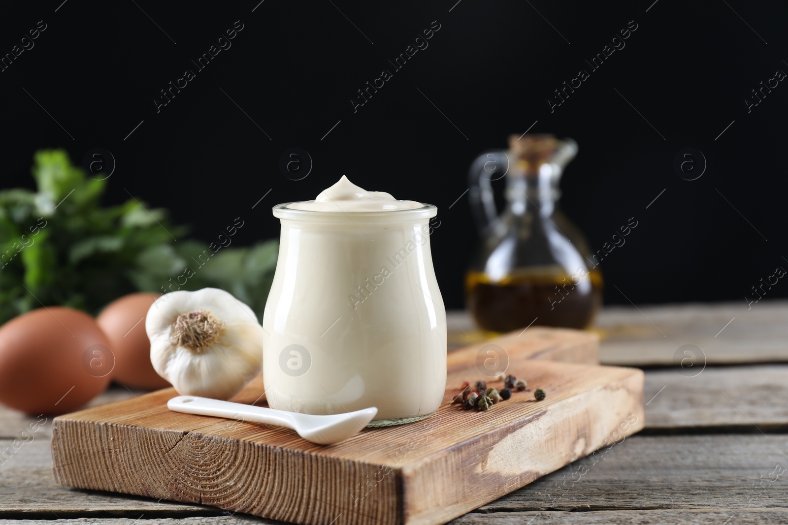 Photo of Fresh mayonnaise sauce in glass jar and ingredients on wooden table. Space for text