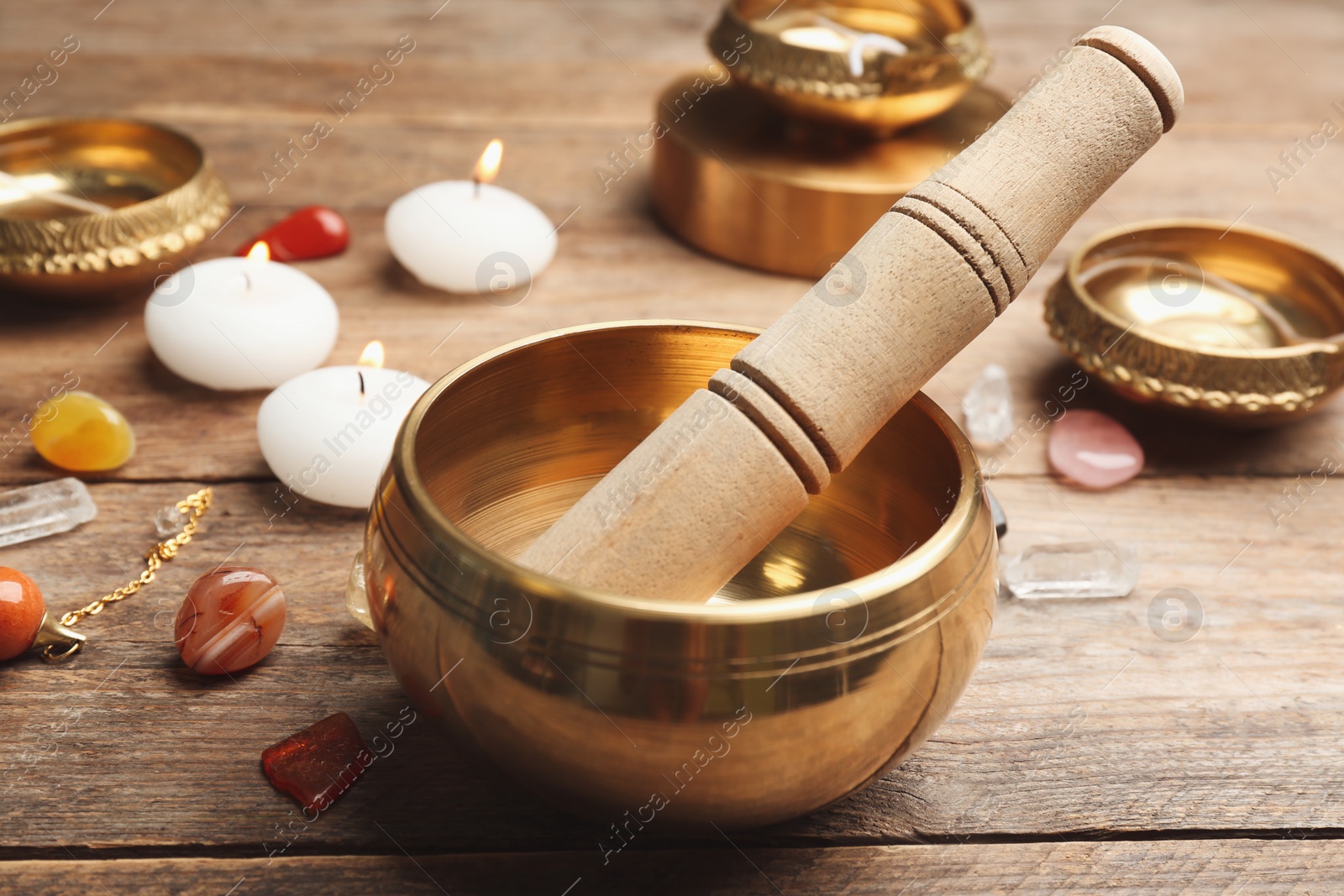 Photo of Composition with golden singing bowl and mallet on wooden table. Sound healing