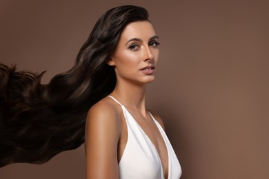 Image of Hair styling. Attractive woman with wavy long hair on brown background