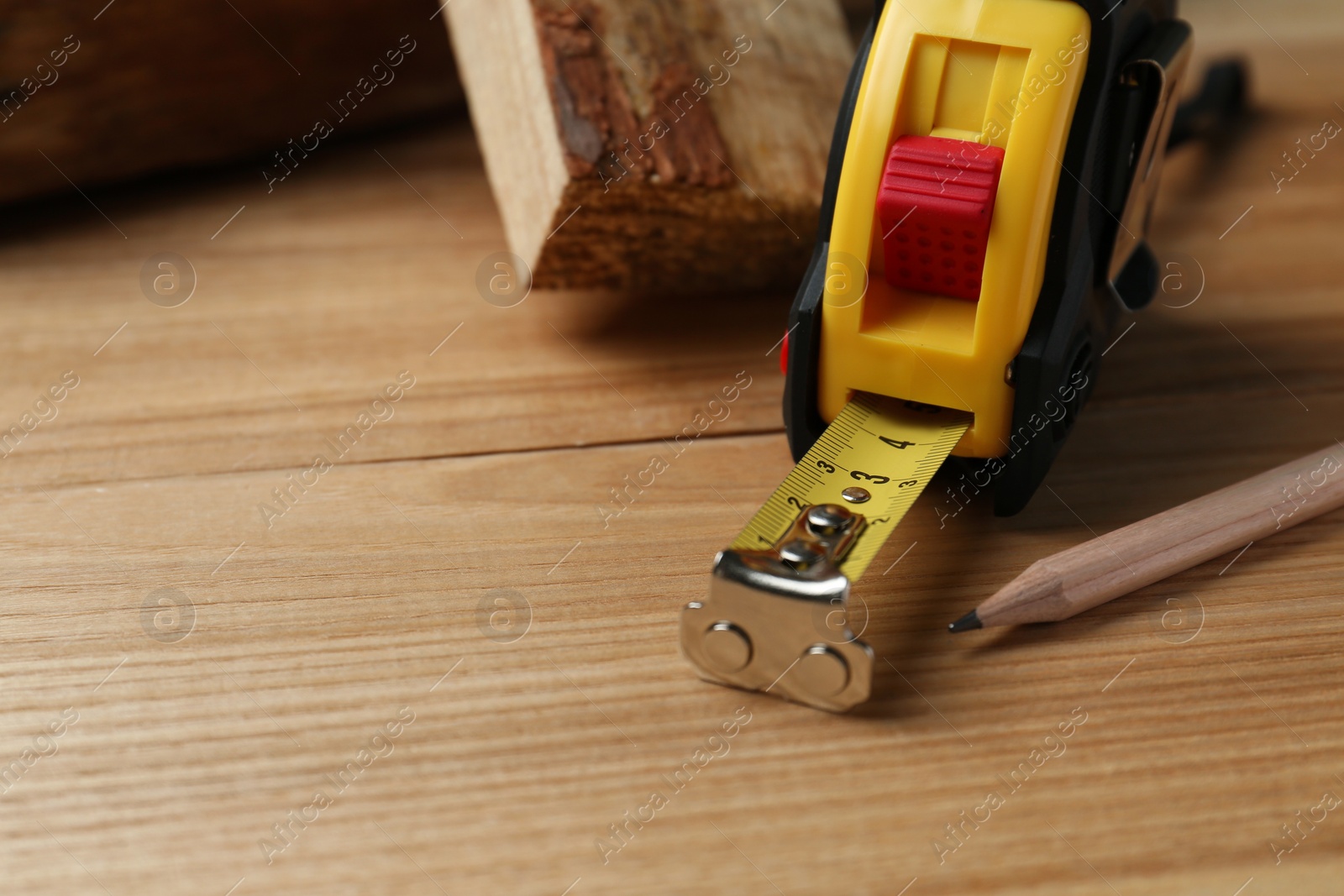 Photo of Tape measure and pencil on wooden table, closeup. Space for text
