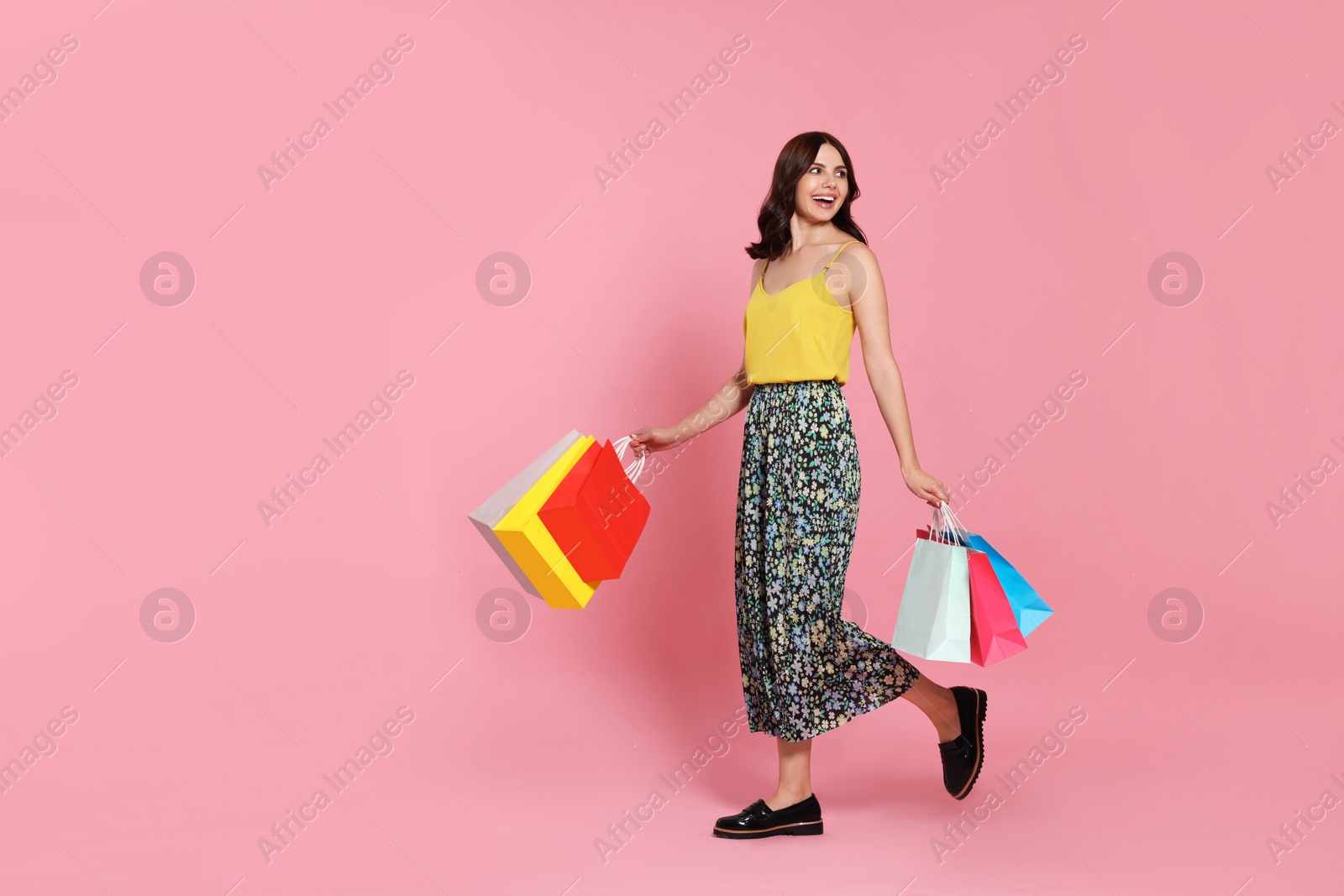 Photo of Beautiful young woman with paper shopping bags on pink background