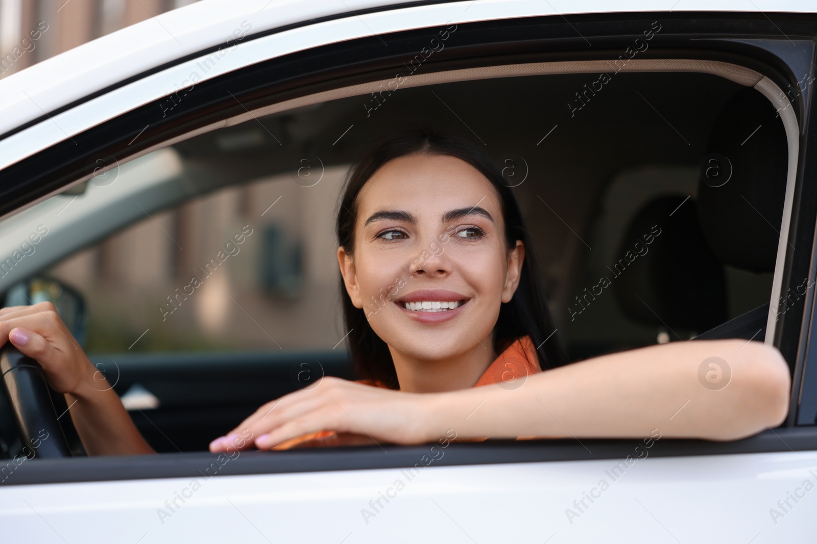 Photo of Enjoying trip. Happy young woman in car, view from outside