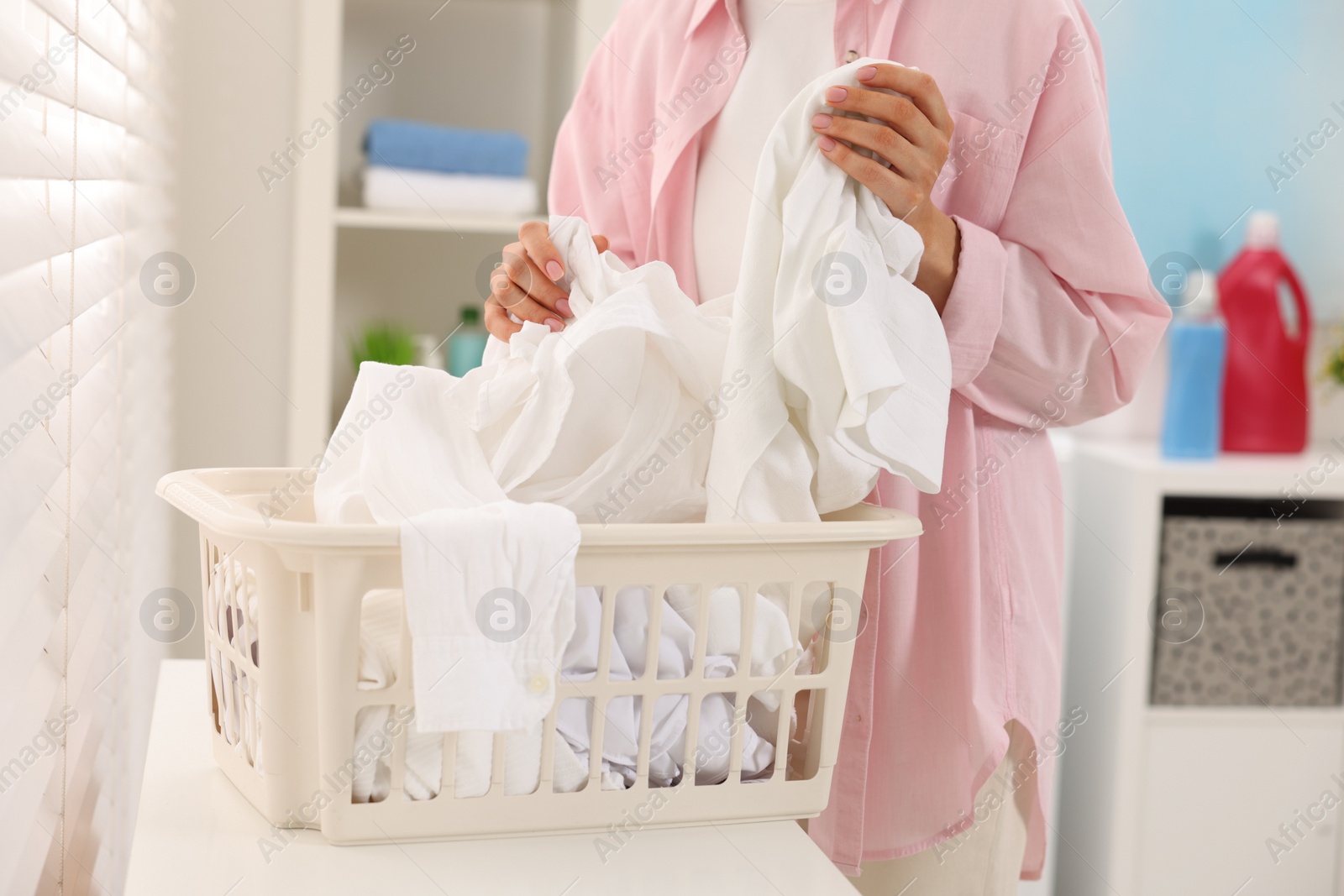 Photo of Woman taking laundry from basket indoors, closeup