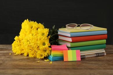 Set of stationery and flowers on wooden table near chalkboard. Teacher's Day