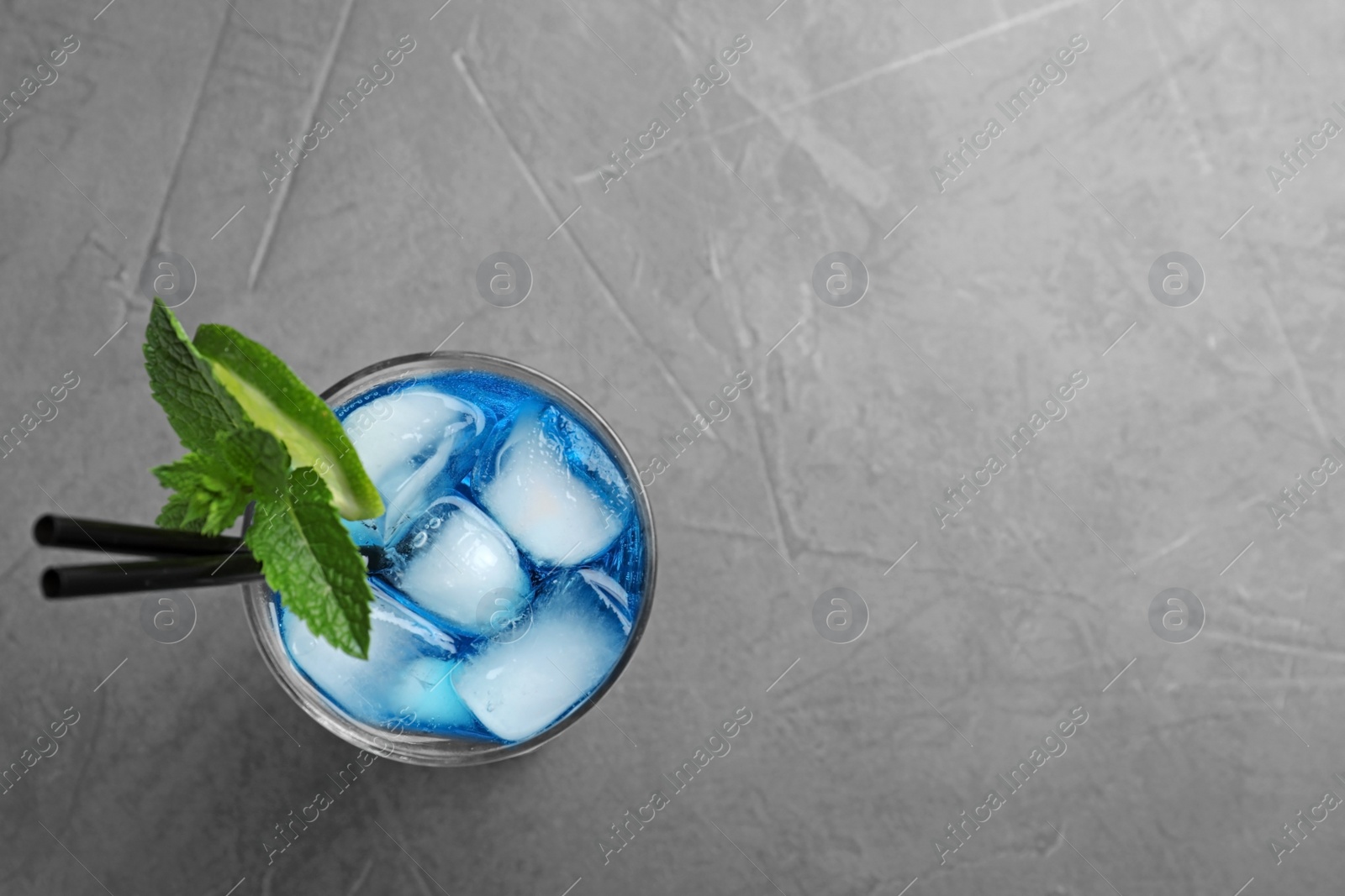 Photo of Glass of tasty refreshing cocktail with mint and lime on grey background, top view. Space for text
