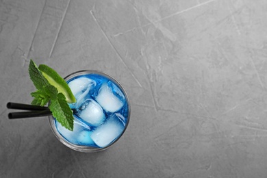 Glass of tasty refreshing cocktail with mint and lime on grey background, top view. Space for text