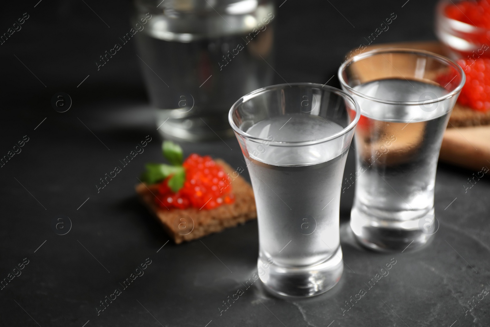 Photo of Cold Russian vodka on black table, closeup view