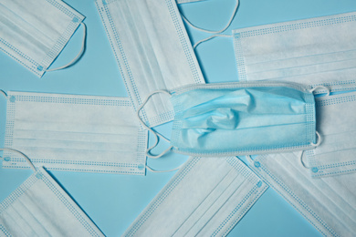 Photo of Disposable face masks on light blue background, flat lay. Protective measures during coronavirus quarantine