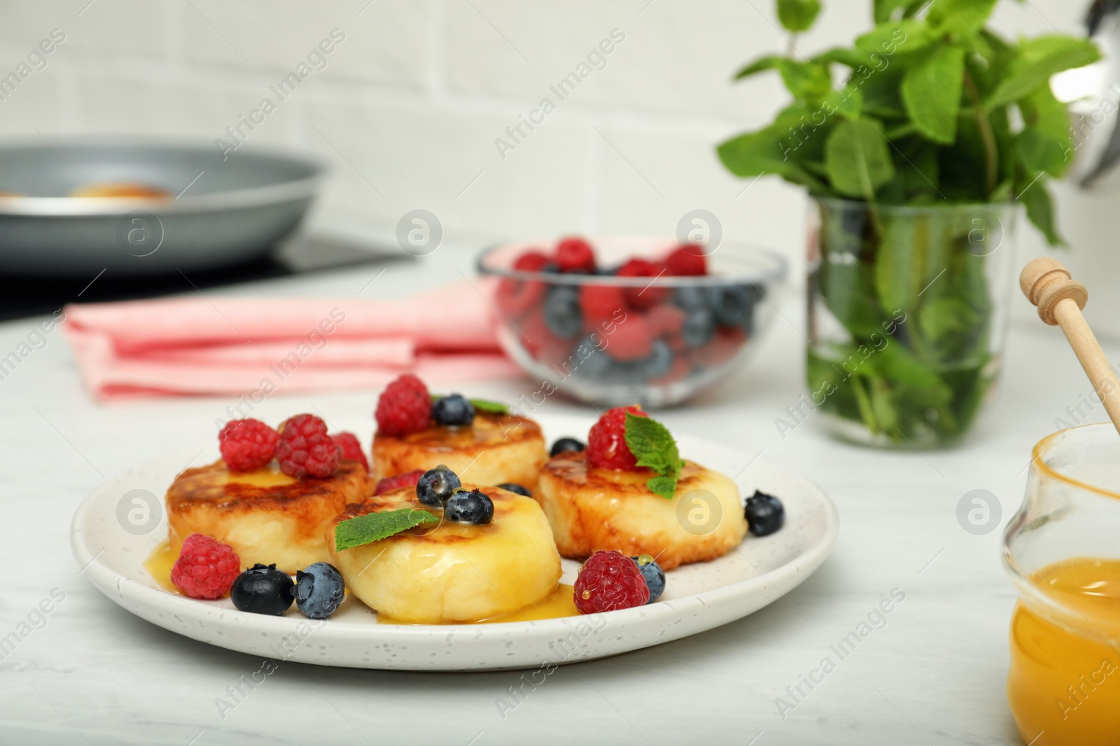 Photo of Delicious cottage cheese pancakes with fresh berries and mint on white countertop