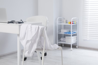 Photo of White doctor's gown hanging on chair in clinic