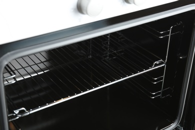 Photo of Open empty electric oven with rack, closeup