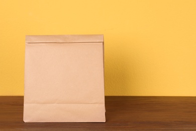 Paper bag on table against color background. Mockup for design