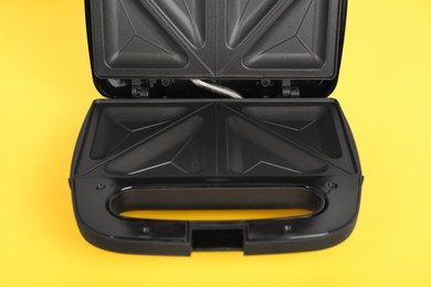 Photo of Open electric sandwich maker on yellow background, closeup