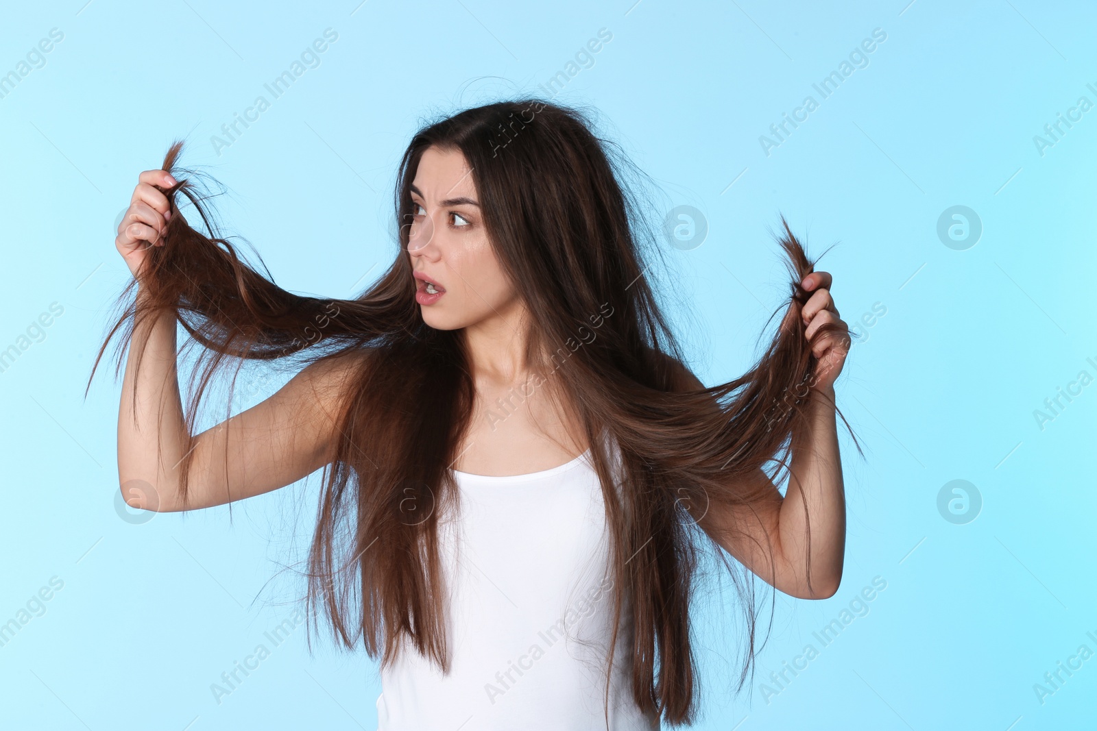 Photo of Emotional woman with damaged hair on color background. Split ends