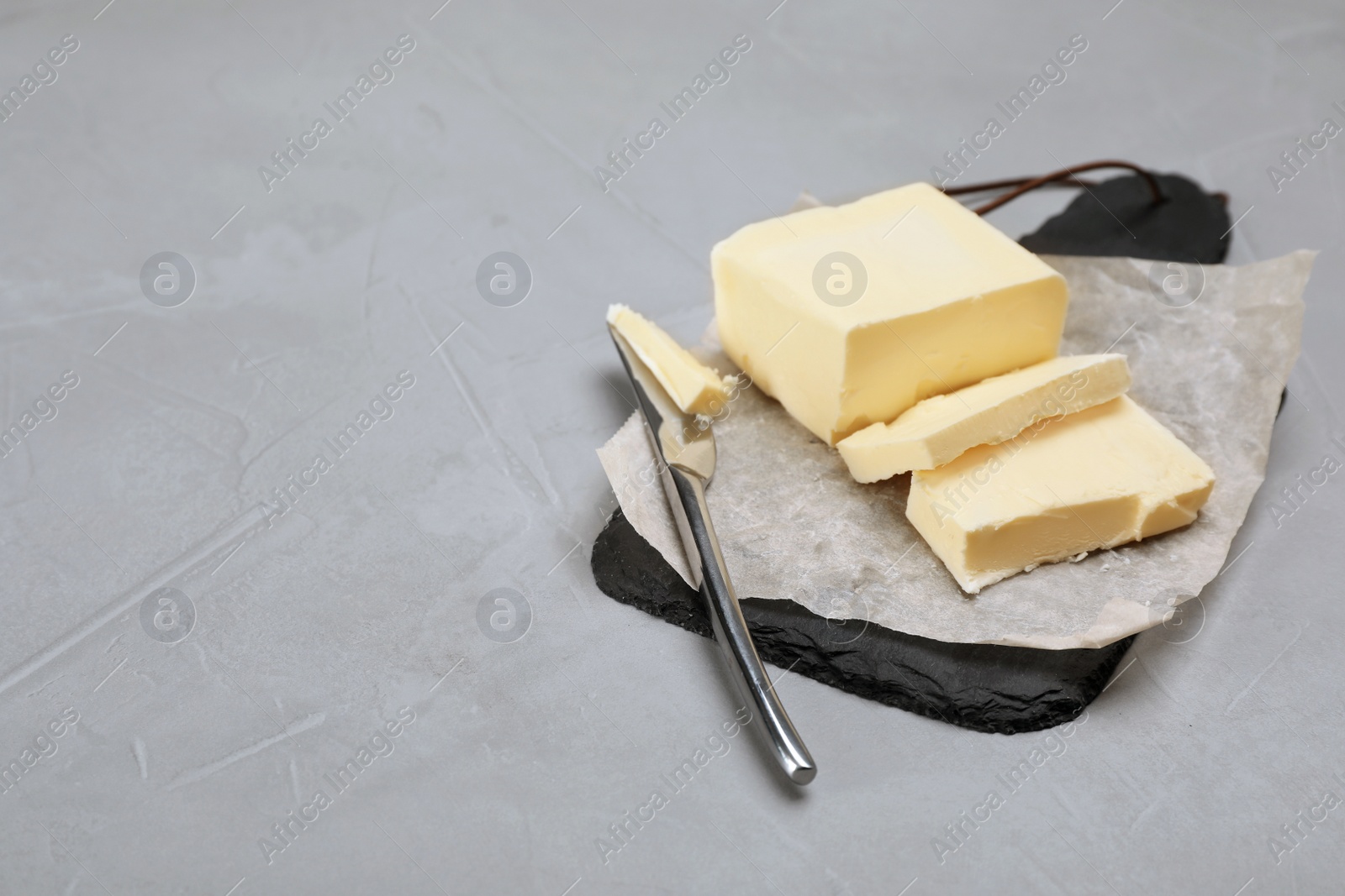 Photo of Slate board with tasty fresh butter and knife on table