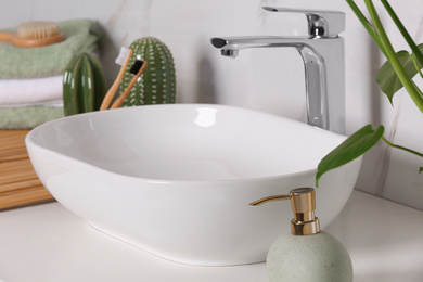 Stylish vessel sink on light countertop in modern bathroom