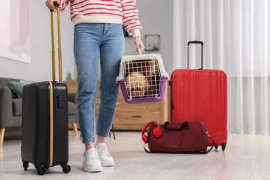 Photo of Travel with pet. Woman holding carrier with dog and suitcase at home, closeup. Space for text