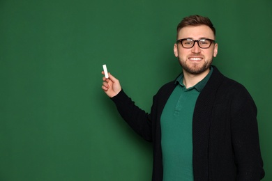 Photo of Portrait of young teacher with chalk on green background. Space for text