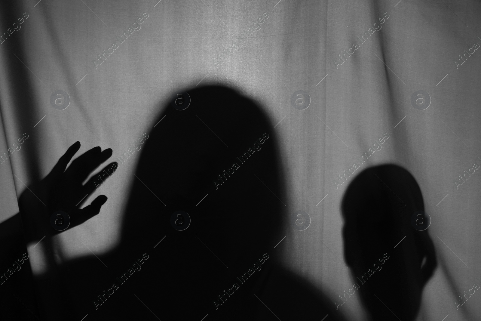 Photo of Silhouette of creepy ghost with skull behind grey cloth