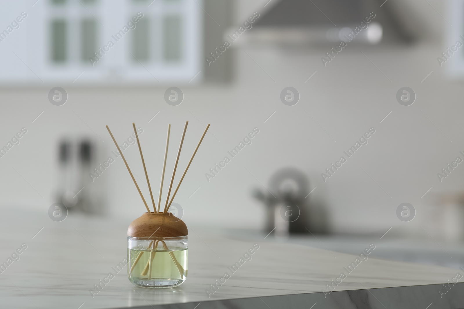 Photo of Aromatic reed air freshener on table indoors. Space for text