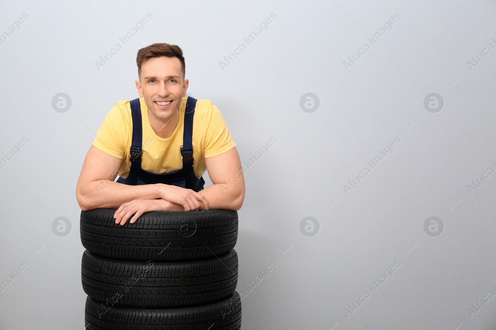 Photo of Male mechanic with car tires on light background