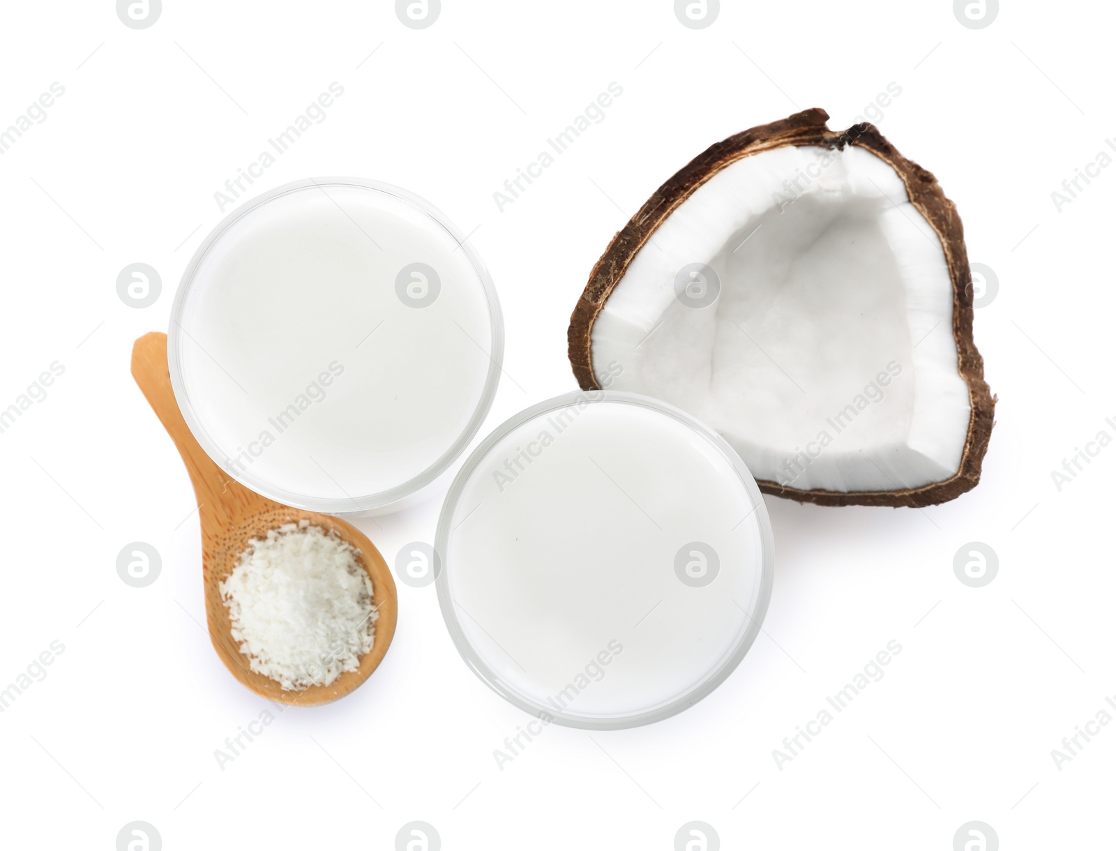 Photo of Glasses of delicious coconut milk, spoon with flakes and coconut isolated on white, top view