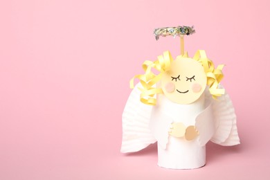 Photo of Toy angel made of toilet paper hub on pink background. Space for text