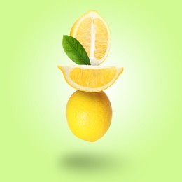 Image of Fresh lemons with leaf falling on pastel green yellow background