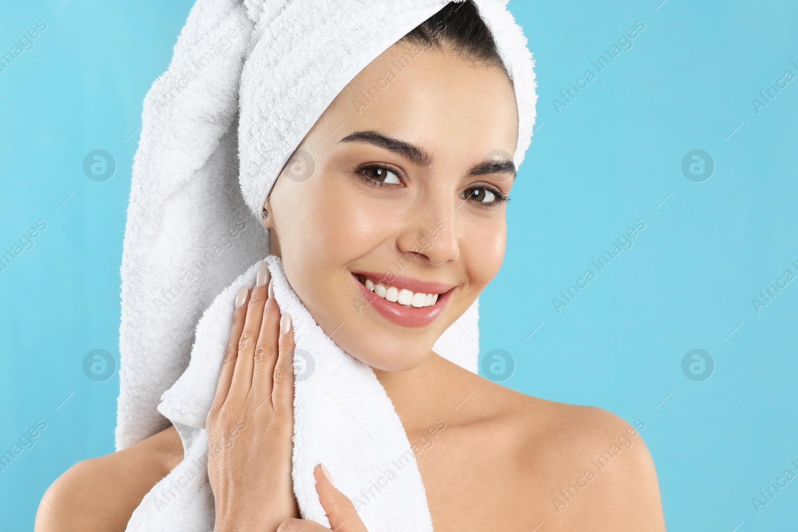 Photo of Young woman wiping body with towel on light blue background