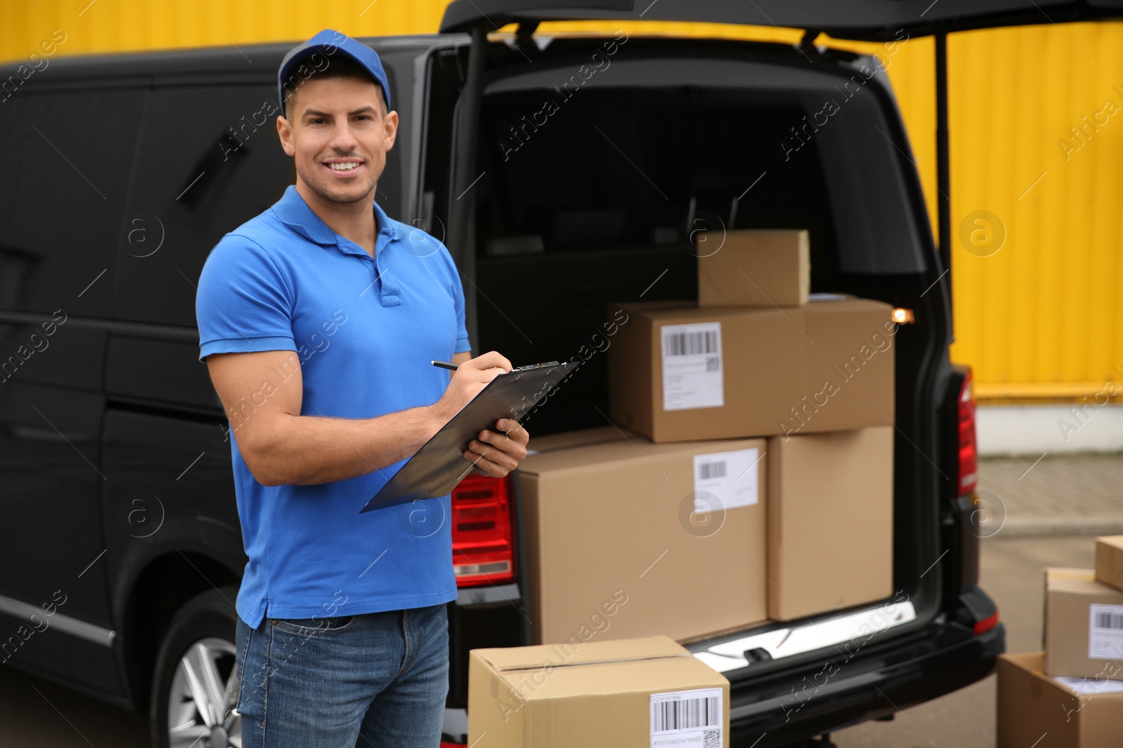 Photo of Courier with clipboard near delivery van outdoors