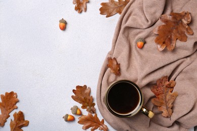 Flat lay composition with cup of hot drink and autumn leaves on light grey textured table. Space for text