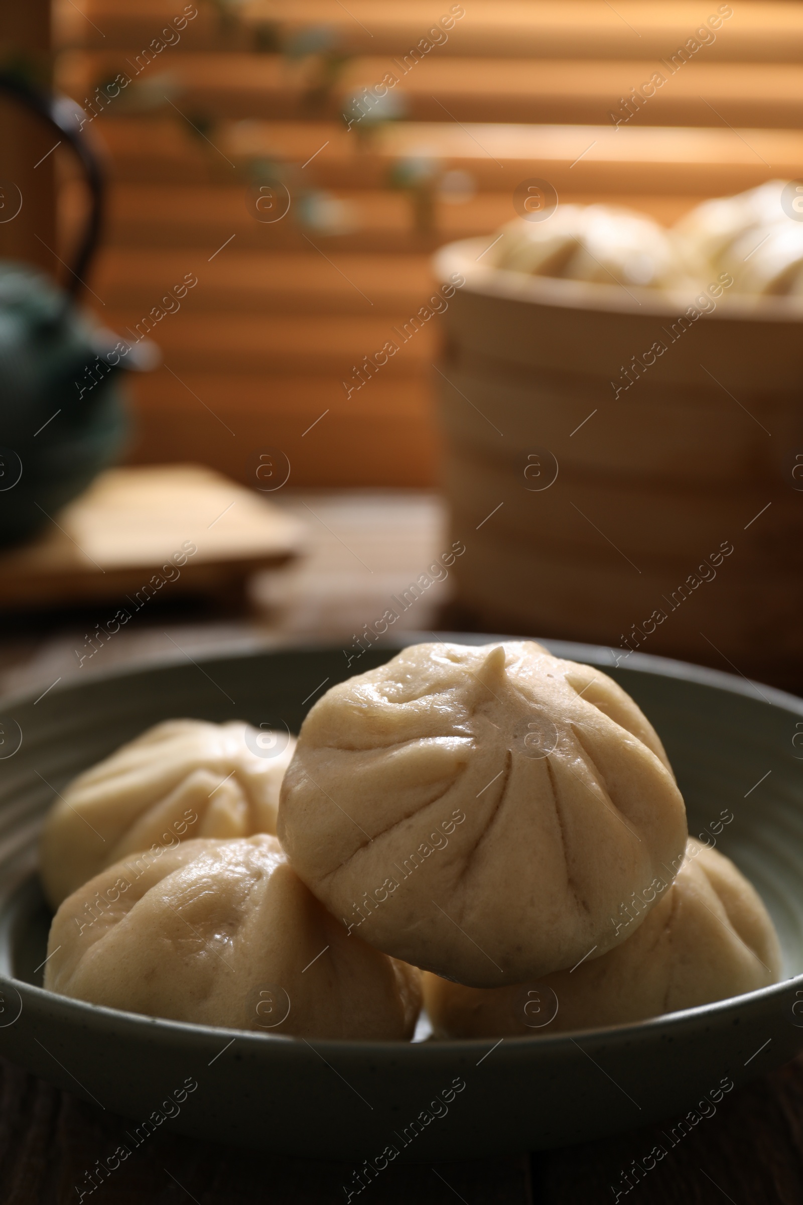 Photo of Delicious bao buns (baozi) in bowl on table, closeup