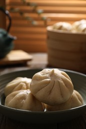 Photo of Delicious bao buns (baozi) in bowl on table, closeup