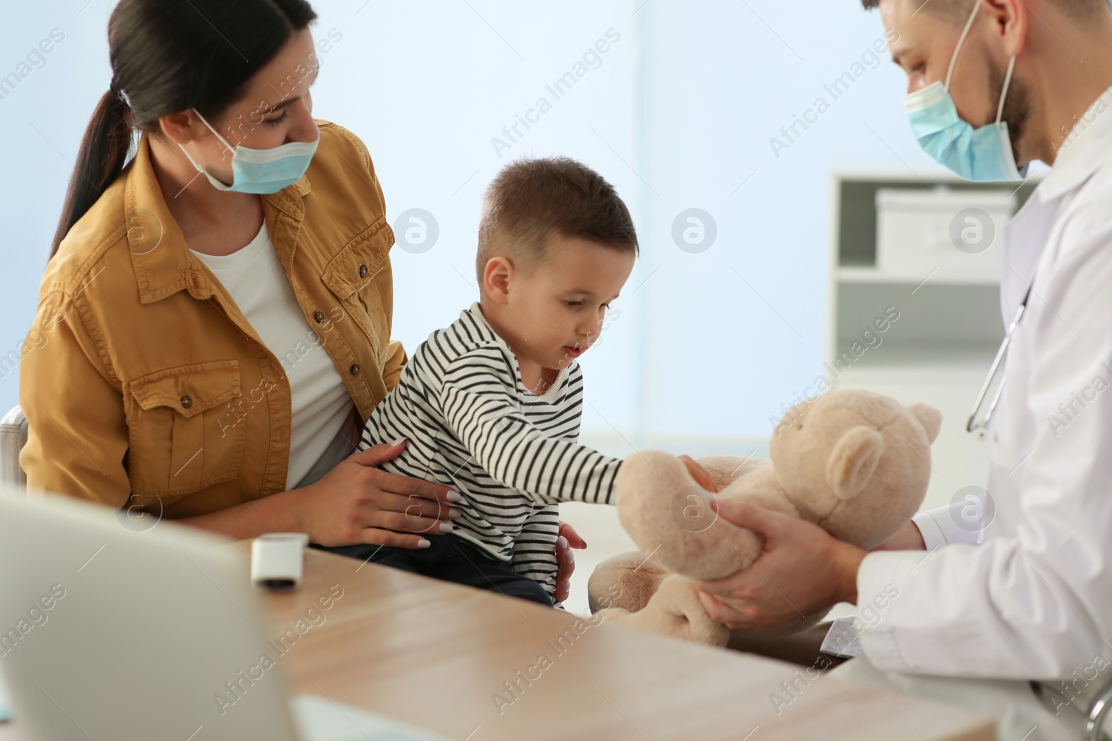 Photo of Mother and son visiting pediatrician in hospital. Doctor playing with little boy