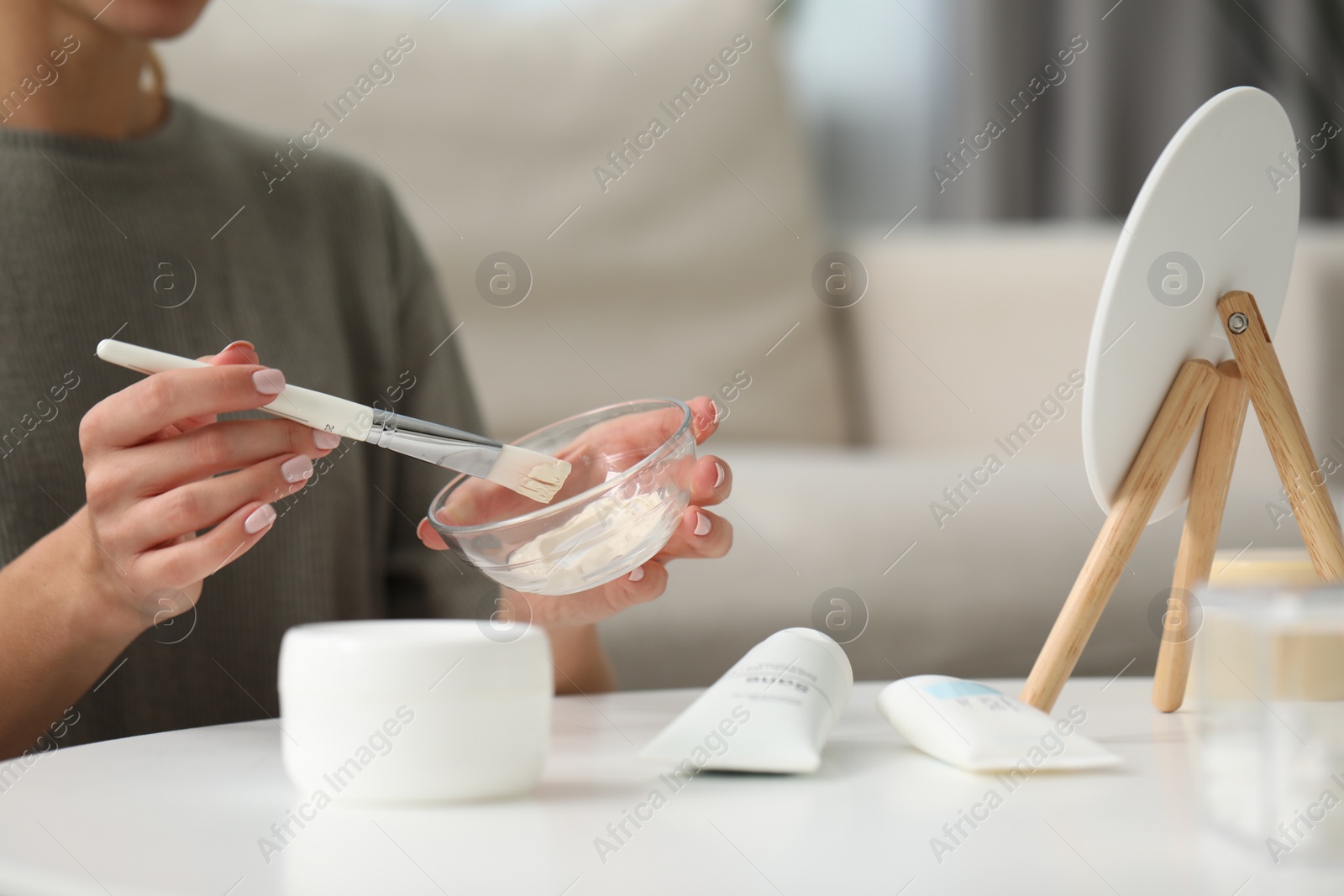 Photo of Young woman preparing face mask in front of mirror at home, closeup. Spa treatments